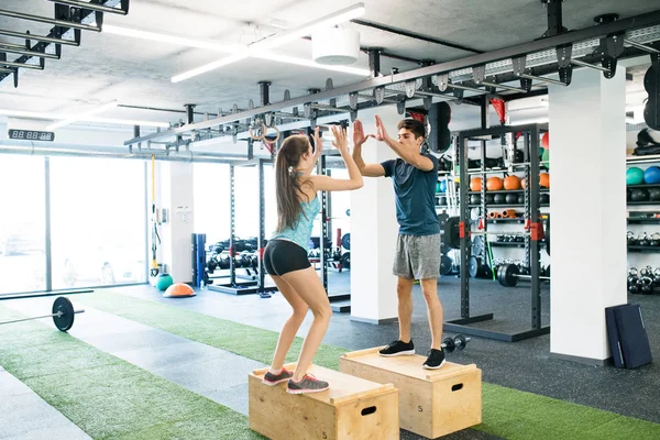 Jeune couple en forme faisant de l'exercice dans la salle de gym, faisant des sauts de boîte . — Photo