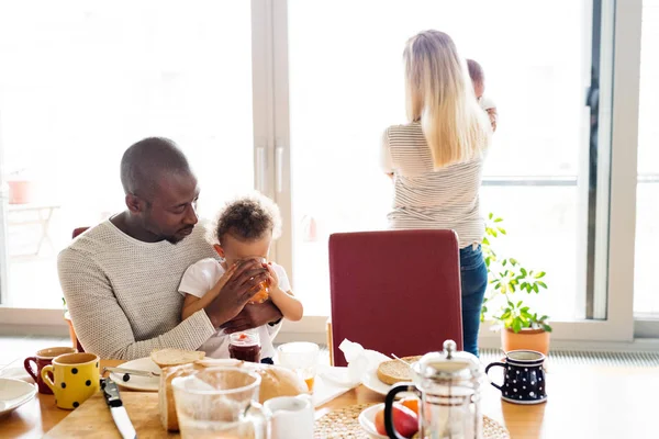 Joven familia interracial con niños pequeños desayunando . —  Fotos de Stock