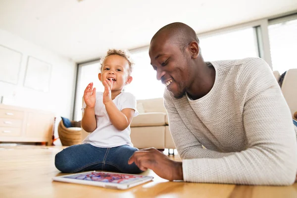Afro-amerykański ojca z małą córeczkę z tabletu w domu. — Zdjęcie stockowe