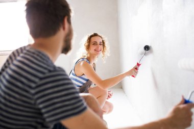 Genç çift yeni evlerinin duvarlarında resim.