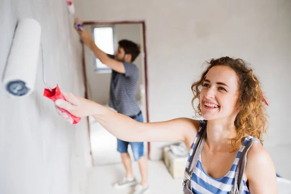 Jong (echt) paar schilderen muren in hun nieuwe huis. — Stockfoto