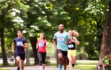 Grup genç sporcuların yeşil güneşli parkta çalıştıran.