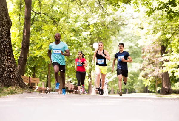 Grupo de jóvenes atletas corriendo en verde parque soleado . — Foto de Stock