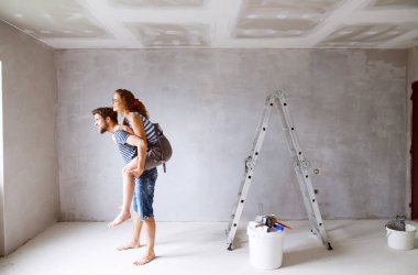Genç çift yeni evlerinin duvarlarında resim.