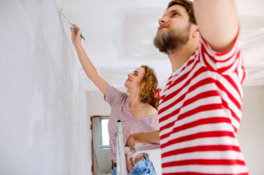 Genç çift yeni evlerinin duvarlarında resim.