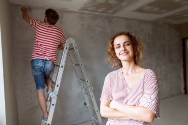 Genç çift yeni evlerinin duvarlarında resim.