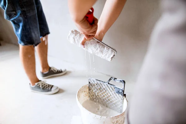 Des jeunes couples méconnaissables peignent des murs dans leur nouvelle maison . — Photo