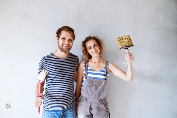 Jeune couple amoureux peignant des murs dans leur nouvelle maison . — Photo