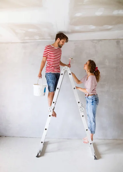 Jovem casal paredes de pintura em sua nova casa . — Fotografia de Stock