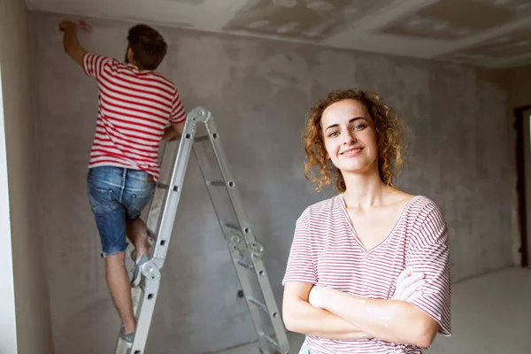 若いカップル彼らの新しい家で絵画の壁. — ストック写真
