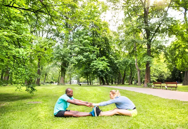 Pareja corriendo estirándose y calentándose en el parque antes del entrenamiento —  Fotos de Stock