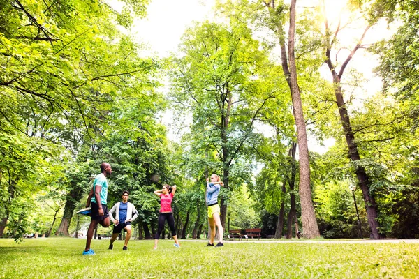 Grupo de jóvenes corredores estirándose y calentándose en el parque . — Foto de Stock
