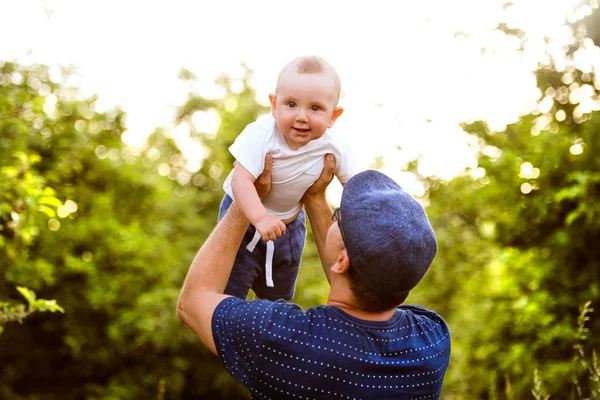 Unga far i naturen håller baby son i armarna. — Stockfoto