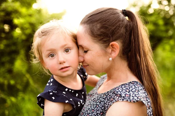 Jonge moeder in de natuur houden dochtertje in de armen. — Stockfoto