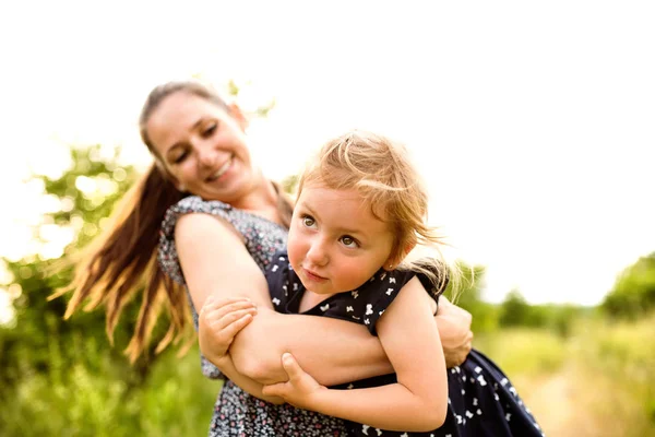 Mooie moeder haar dochter spinnen. Zonnige zomer natuur. — Stockfoto