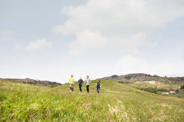Grup yaşlılar dışında yeşil tepeler üzerinde çalışan.