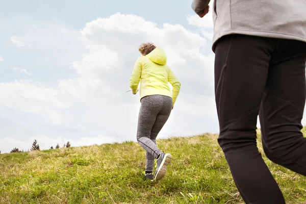 Pareja mayor irreconocible corriendo afuera en verdes colinas . — Foto de Stock