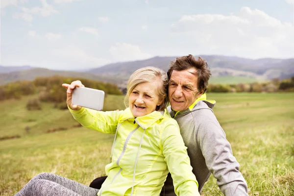 Corredores seniores ativos na natureza tomando selfie com telefone inteligente . — Fotografia de Stock