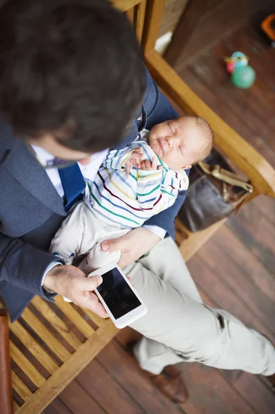 正面玄関の上に座っての赤ん坊の娘を持ったビジネスマン. — ストック写真