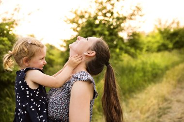 Doğada küçük kızın kollarında tutan genç anne.