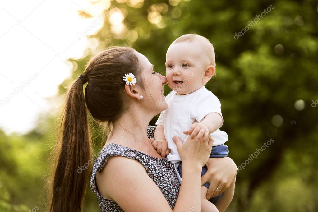 Young mother in nature holding little baby son in the arms.