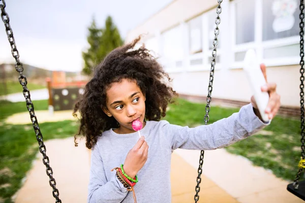 棒棒糖采取自拍照与 smartphon 的非洲裔美国女孩 — 图库照片