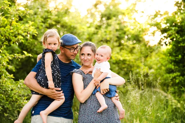 Mladá rodina s malými dětmi v slunné letní přírody — Stock fotografie