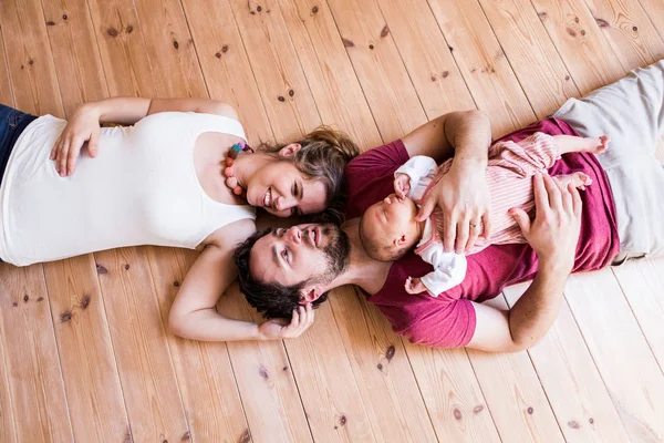 Ouders houden hun schattige baby dochter, houten achtergrond. — Stockfoto