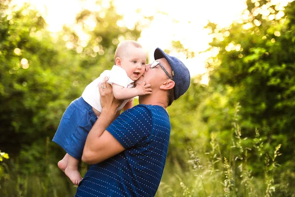 Unga far i naturen håller baby son i armarna. — Stockfoto