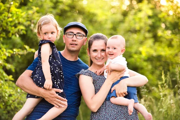 Junge Familie mit kleinen Kindern in sonniger Sommernatur — Stockfoto