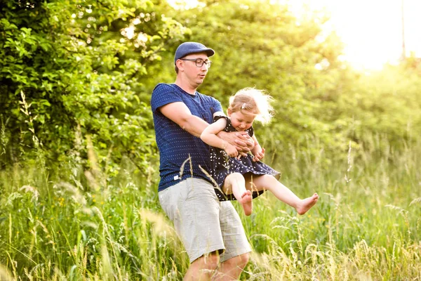 Il giovane padre che fa girare sua figlia. Natura estiva soleggiata . — Foto Stock