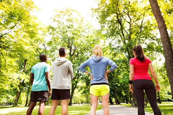 Grupo de jóvenes atletas preparados para correr en verde parque soleado . — Foto de Stock