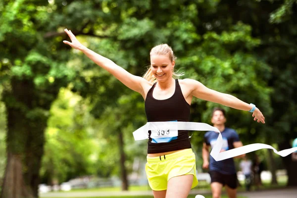 Young woman running in the crowd crossing the finish line. — Stock Photo, Image