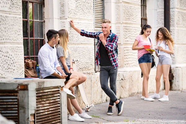 Group of teenage students talking in front of university. — Stock Photo, Image