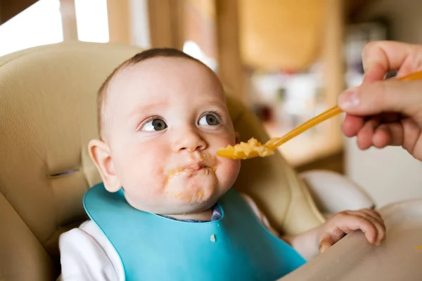 Madre irreconocible en casa alimentando a su hijo pequeño . —  Fotos de Stock