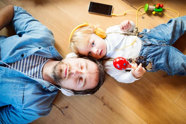 Vader en zoon met smartphone en oortelefoons, luisteren muziek. — Stockfoto