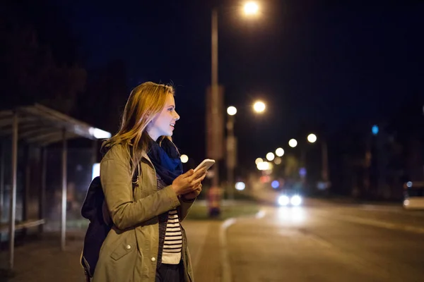 Kvinna i staden på natten innehav smartphone, textning. — Stockfoto