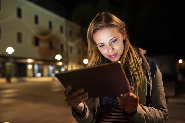 Kobieta w mieście w nocy gospodarstwa tablet, czytanie coś. — Zdjęcie stockowe