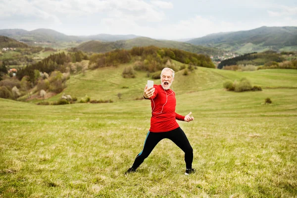 Aktiv senior löpare i naturen tar selfie med smart phone. — Stockfoto