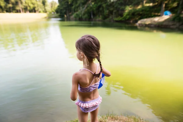 Gadis kecil berdiri di danau. Musim panas Sunny . — Stok Foto