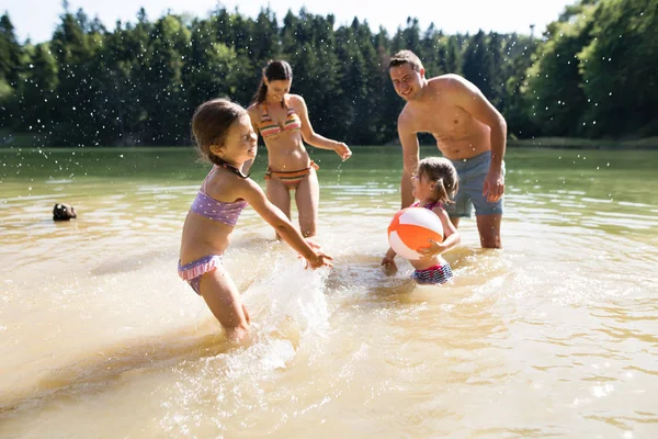 Matku, otce a dcery v jezeře. Slunečné léto. — Stock fotografie