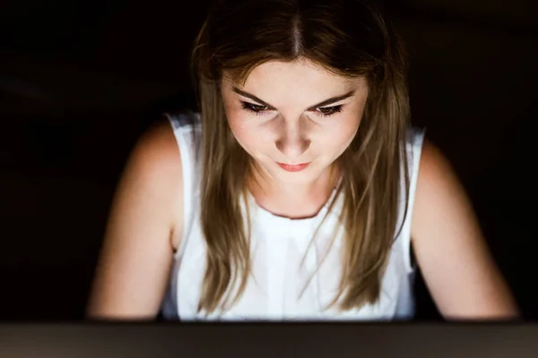 Businesswoman in front of computer screen in office at night.