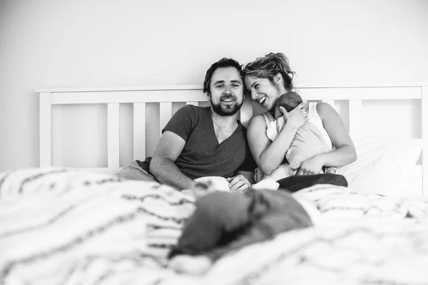 Unga föräldrar i sängen med sina söta små barn — Stockfoto
