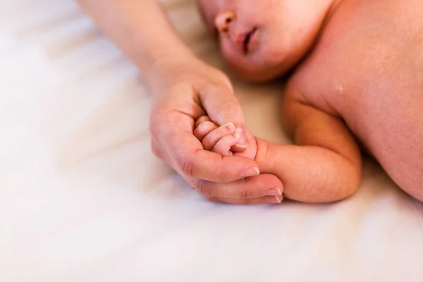 Filha recém-nascida irreconhecível deitada na cama — Fotografia de Stock