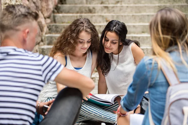 Estudiantes adolescentes sentados en escalones de piedra frente a la universidad . —  Fotos de Stock