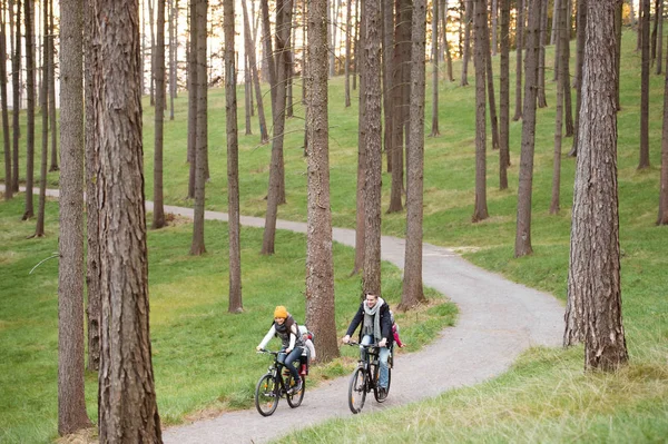 Familia joven en ropa de abrigo en bicicleta en el parque de otoño — Foto de Stock
