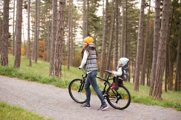 Junge Mutter und Tochter auf Fahrrad im Herbstpark — Stockfoto