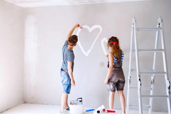 Couple painting heart on the wall in their house. — Stock Photo, Image