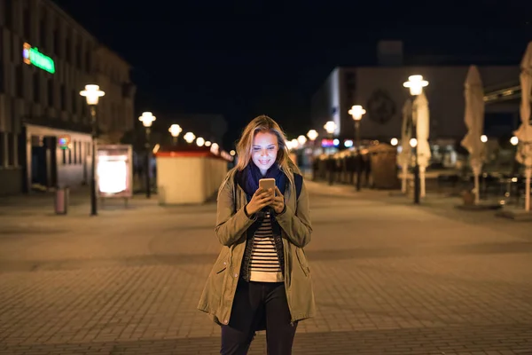 Kobieta w mieście w nocy gospodarstwa smartphone, SMS-y. — Zdjęcie stockowe