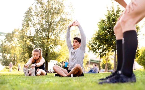 Group of young runners stretching and warming up in park. — Stock Photo, Image